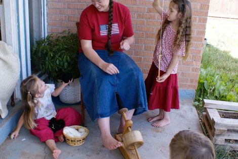 mom spinning wool with little girls