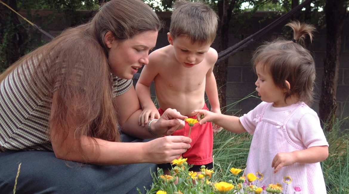 mom and kids looking at flower